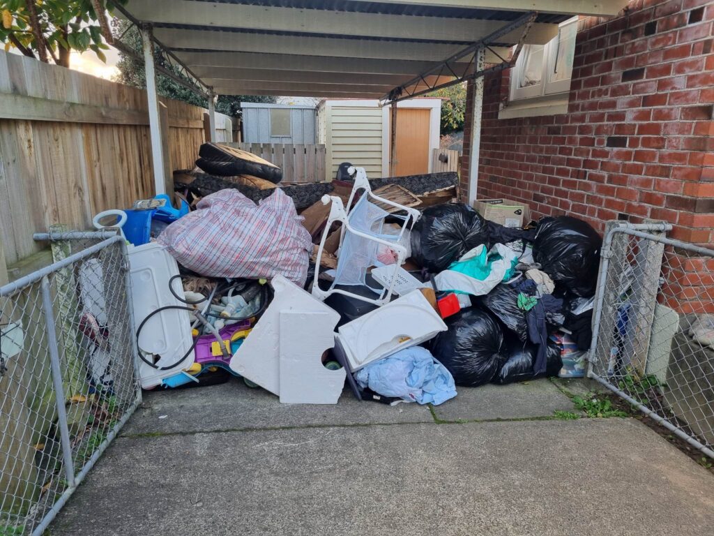 Large pile of household rubbish in a carport before removal in Palmerston North