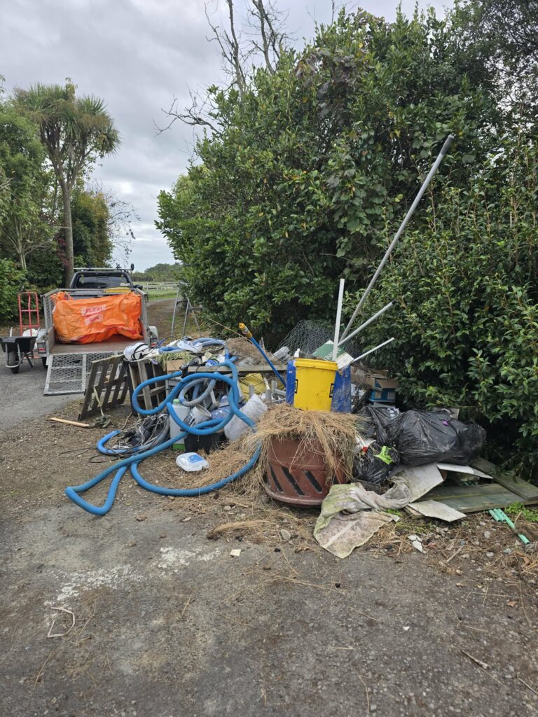 Mixed outdoor rubbish beside a driveway before removal in Manawatū